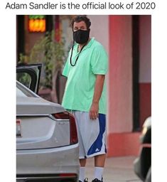 a man wearing a face mask while standing in front of a car with the caption, adam sandler is the official look of 2020