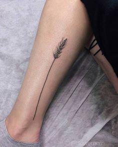 a woman's leg with a single flower tattoo on the left side of her arm