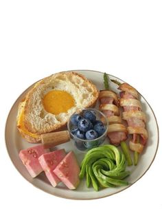 a white plate topped with bacon, watermelon and an egg next to bread