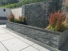 an outdoor garden with stone walls and plants on the sides, along with concrete walkways