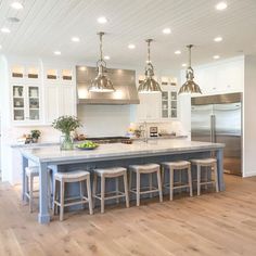 a kitchen island with stools in front of it and lights hanging from the ceiling