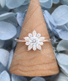 a diamond flower ring sitting on top of a wooden cone