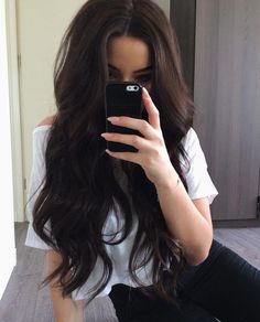 a woman taking a selfie with her cell phone in front of her face while sitting on the floor