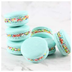 several macaroons with sprinkles on them sitting on a marble surface