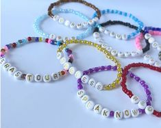 six bracelets with name beads on them sitting next to each other in different colors