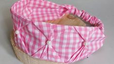 a pink and white checkered hat sitting on top of a wooden basket