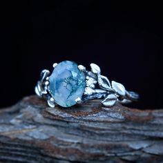 a blue ring with leaves on it sitting on top of a piece of driftwood