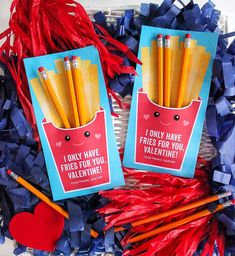 two valentine's day cards with pencils in them and some streamers on the table