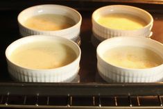 four white bowls filled with soup sitting on top of an oven