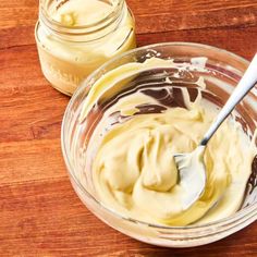 two jars filled with mayonnaise sitting on top of a wooden table next to each other