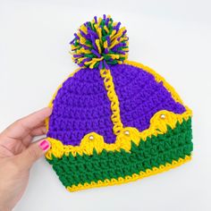 a hand is holding a knitted hat with a pom - pom on it