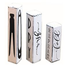 three wooden blocks with black and white writing on them, one has scissors in it