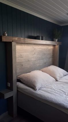 a bed with two pillows on top of it in a room that has blue walls