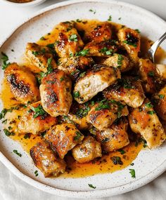 a white plate topped with chicken covered in sauce and garnished with parsley