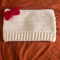 a crocheted white cloth with a red bow laying on top of it's side