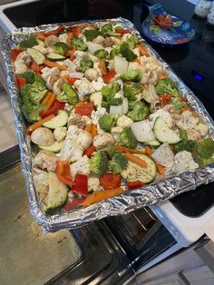 a sheet pan filled with vegetables on top of an oven burner next to a stove