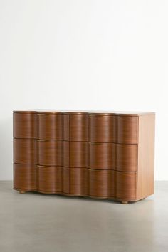 a large wooden dresser sitting on top of a cement floor next to a white wall