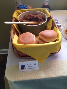 two hamburgers in a basket on top of a table next to a bowl of soup