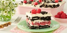 a piece of cake on a plate with raspberries and flowers in the background