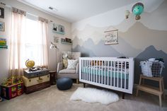 a baby's room with a mountain mural on the wall and a crib