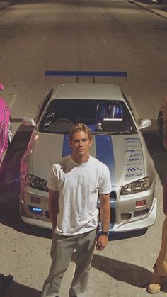 two men standing in front of a white car