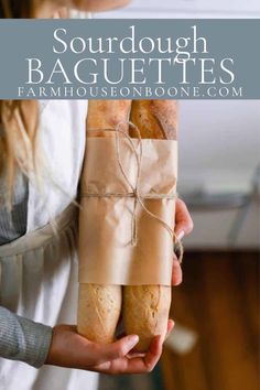 a woman holding two baguettes wrapped in brown paper