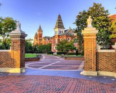 the entrance to an old brick building with two towers on each side and a clock tower in the background