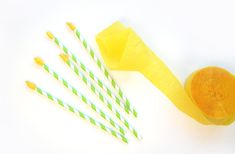 four green and white striped straws next to a yellow cupcake on a table