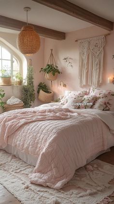 a bed with pink comforter and pillows in a room next to a large window