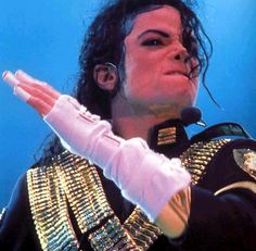 michael jackson performing on stage with his hands in the air and wearing gold bracelets