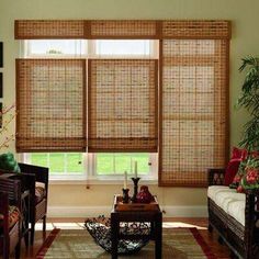 a living room filled with lots of furniture and windows covered in bamboo blind shades on top of them