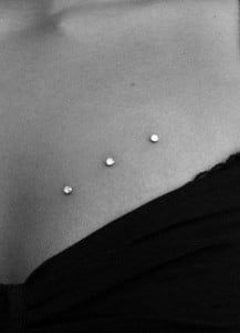 black and white photograph of a woman's stomach with three studs on it