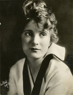 an old black and white photo of a woman with short hair wearing a collared shirt