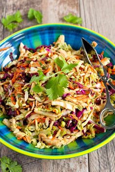 a blue bowl filled with coleslaw and carrots on top of a wooden table