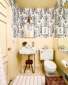 a bathroom with yellow walls and floral wallpaper on the walls, along with a white toilet and sink