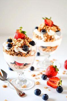 yogurt parfait with berries and granola in glass bowls on white surface