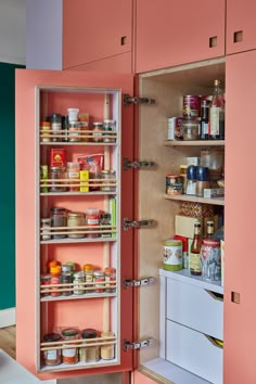 an organized pantry with pink cabinets and shelves filled with spices, condiments, and other items