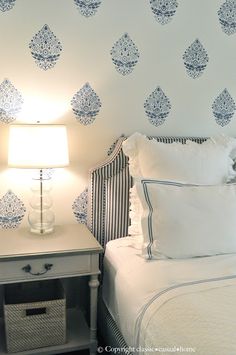 a white bed sitting next to a night stand with a lamp on top of it