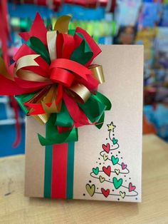 a card with a christmas tree on it sitting on a table next to a red ribbon