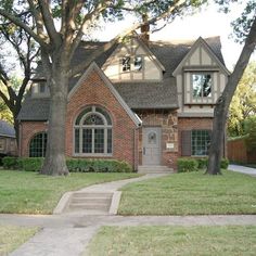 a brick house with trees in the front yard