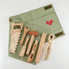 several wooden tools are laid out on a green cloth, including scissors and pliers