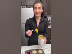 a woman is holding a cup and spoon over a muffin tin