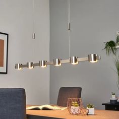 a modern light fixture hanging from the ceiling above a table with a book on it