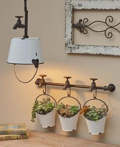 three potted plants are hanging on the wall next to a lamp and some books