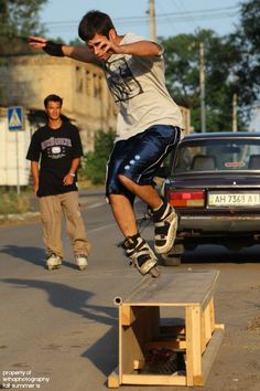 a man riding a skateboard down the side of a wooden ramp next to a car