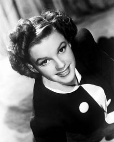 an old black and white photo of a young woman with curly hair smiling at the camera