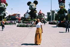 a woman is standing in front of mickey mouses at the entrance to disney world