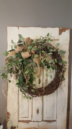 a wreath hanging on the side of a door with green leaves and burlocks