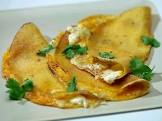 two tortilla shells with cheese and parsley on top, sitting on a white plate