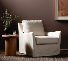 a white chair sitting next to a small table with a vase on top of it